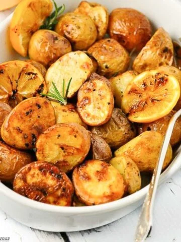 overhead view of a bowl of roast potatoes with lemon.