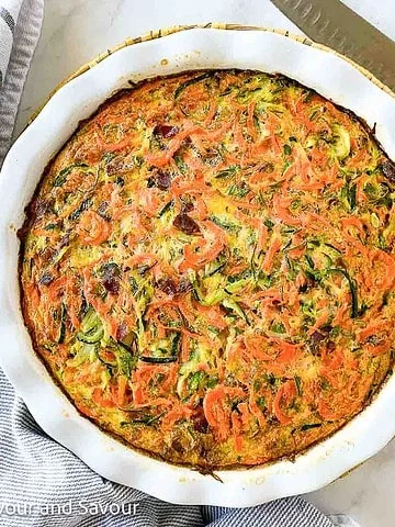 A baking dish with crustless zucchini carrot quiche with rosemary and bacon.