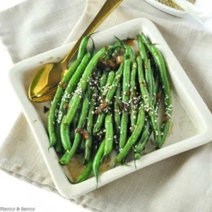 Sesame Ginger Green Beans in a square serving dish with a gold spoon