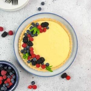 Lemon Curd Tart in a round pan with fresh berries