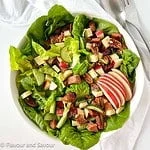 Overhead view of a bowl of salad with smoked salmon, apples, cheese and pecans.