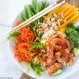 Overhead view of Vietnamese Prawn (Shrimp) Noodle Bowl with snow peas, carrots, mango, avocado and fresh herbs