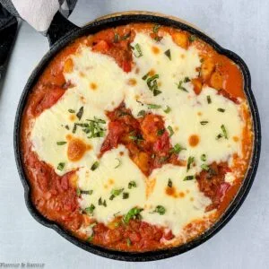 a cast iron skillet with cheesy tomato gnocchi bake