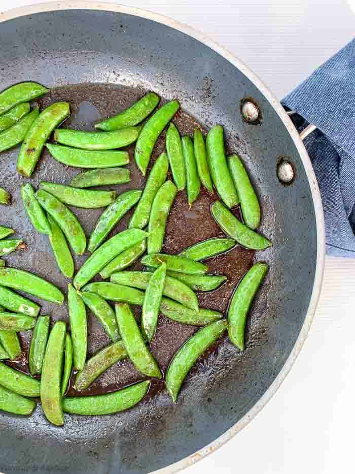 Sautéed snow peas in a skillet.