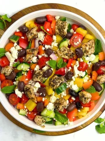 Overhead view of a round shallow bowl with Greek Chicken Salad with Mint leaves.