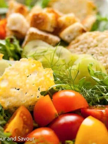 Parmesan crisps on top of a mixed vegetable salad.