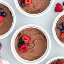 Sugar free chocolate pudding in ramekins with berries on top.