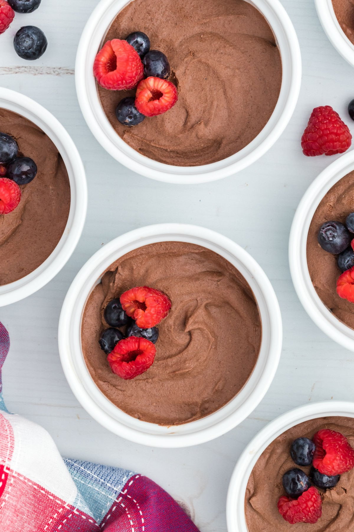 Sugar free chocolate pudding in ramekins with berries on top.